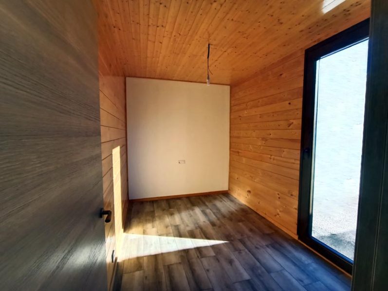 Habitación vacía con paredes de madera y gran ventana que ilumina el espacio.