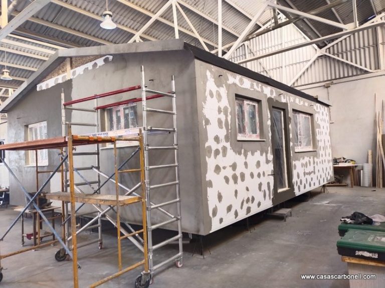 Casa prefabricada en construcción, con andamios y una estructura sin terminar.