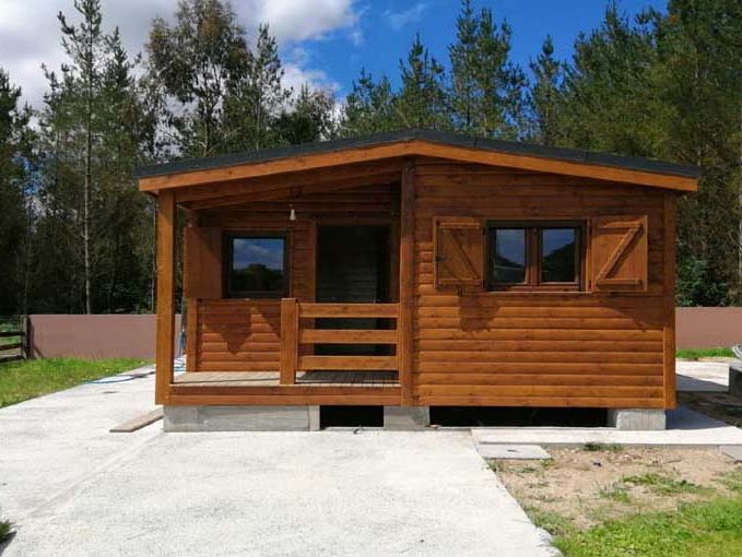 Casas Prefabricadas CMC 1ª Vivienda de madera con porche, ventanas y un entorno natural arbolado.