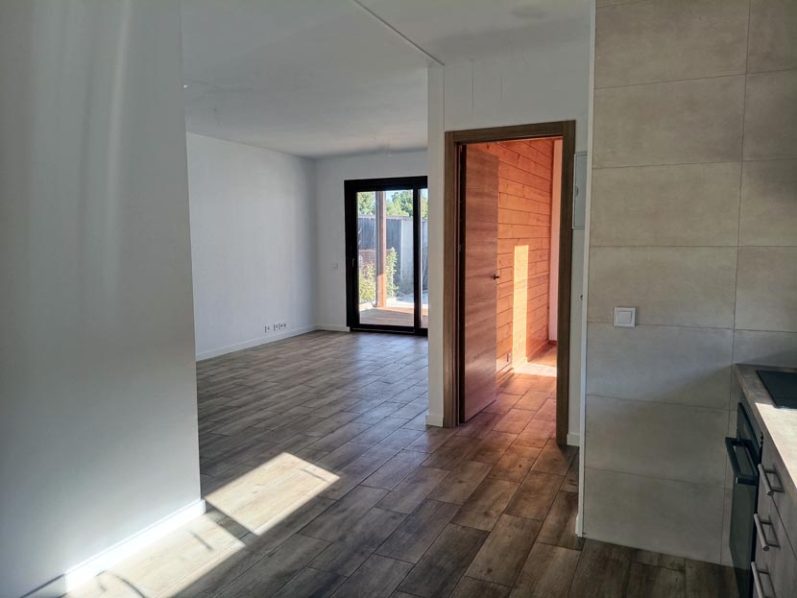 Interior de una habitación vacía con luz natural y un acceso a otro espacio.