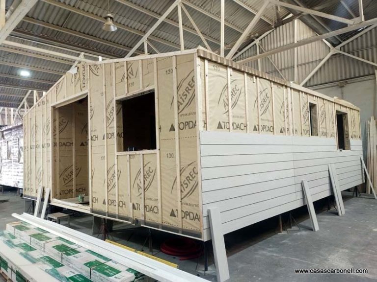 Estructura de una casa prefabricada en construcción, con paneles de madera y ventanas sin colocar.