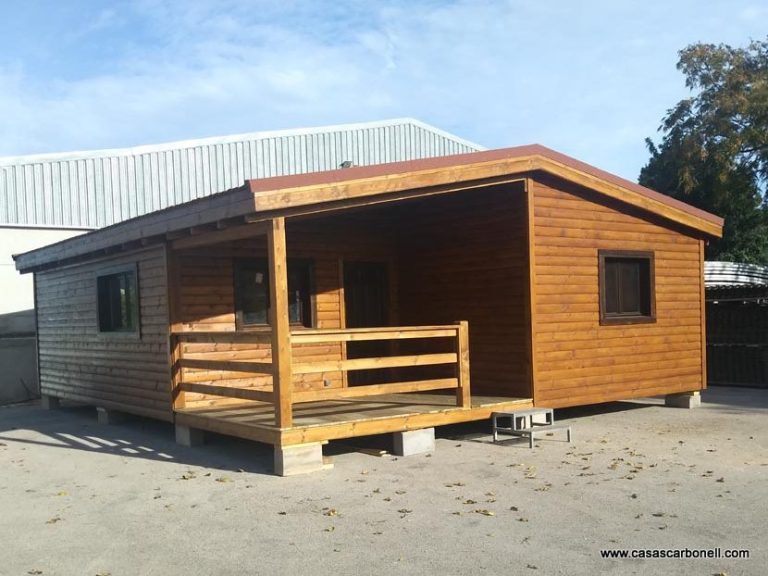 Casa prefabricada de	80 m² de madera con porche y ventanas, situada en un entorno abierto y soleado.