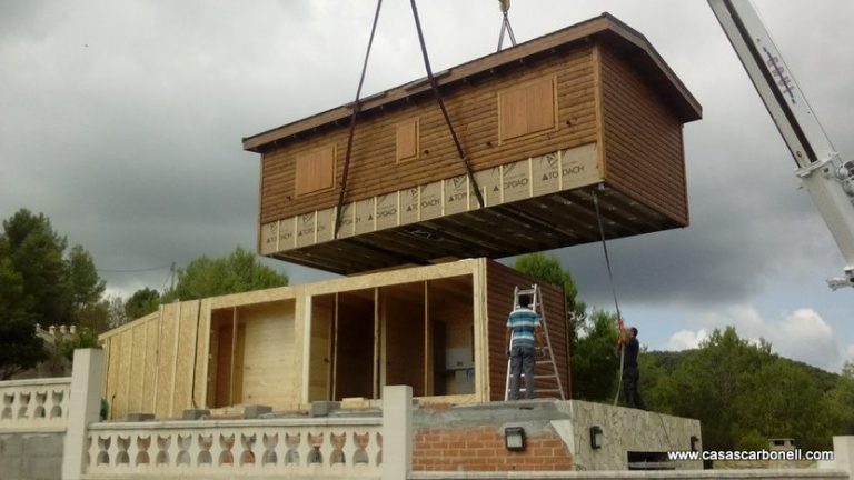 Una casa prefabricada España, modular siendo levantada por grúas, con un trabajador en la base.