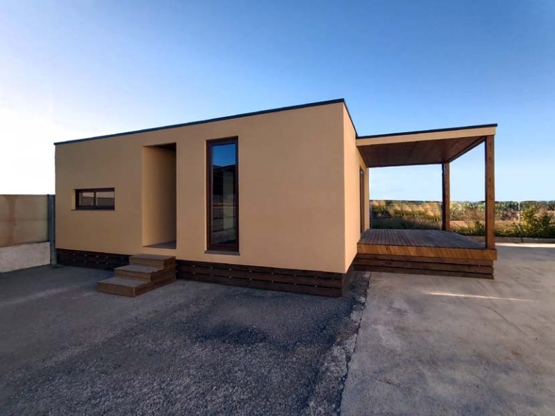 Casa moderna de un solo piso con un porche y una fachada de color claro.