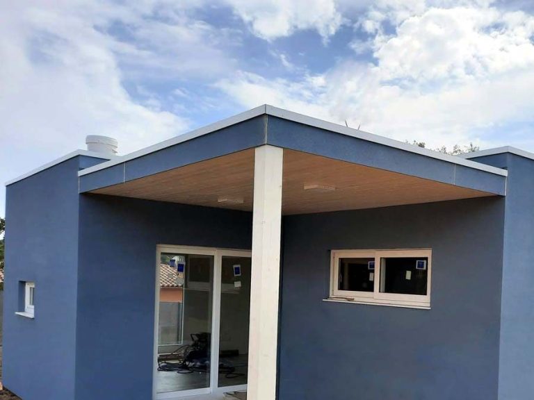 Casas Prefabricadas CMC 1ª Vivienda de color azul con techo sobresaliente y ventanas.